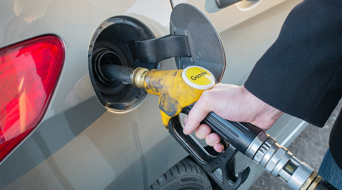 A man putting petrol into his car using a yellow coloured pump